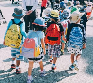 School children walking in a group while wearing colorful backpacks.